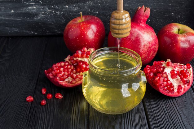 Close up on honey, pomegranate and red apples on the black background