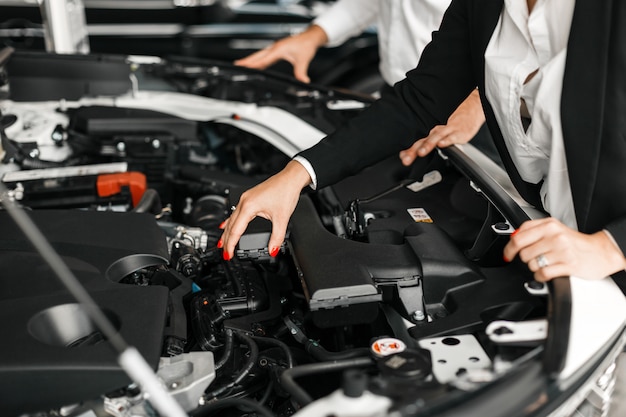 車のボンネットを閉じます。モーターに触れる女性の手。