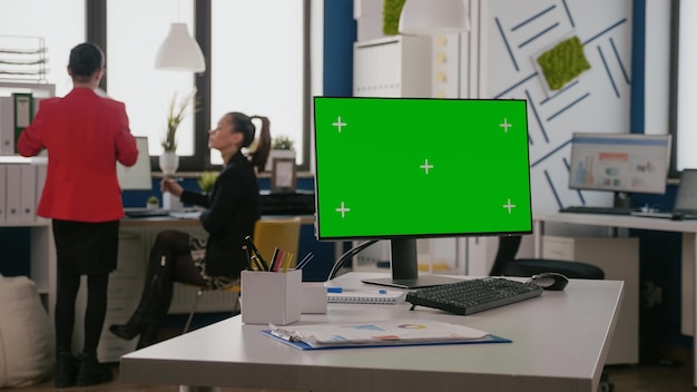 Close up of horizontal green screen on computer in business office. Isolated chroma key with blank mock up background and copy space template on monitor display at empty desk in space.