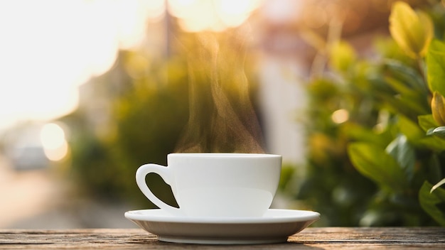 自然ビューの背景に蒸し煙でホットコーヒーカップを閉じます。