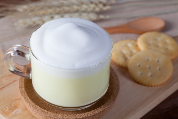 Vicino latte caldo verde con biscotti su lastra di legno sul tavolo di legno per la prima colazione.