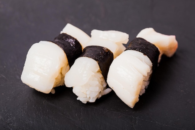 Close-up of Hotate nigiri sushi with scallop on a black slate background