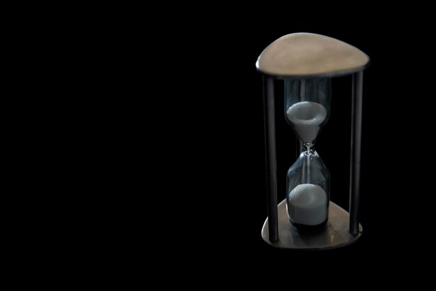 Photo close-up of hourglass against black background