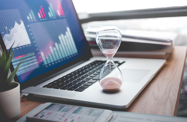 Photo close-up of hourglass on laptop