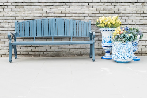 Close-up houten stoel met valse bloemen in vaas op vage bakstenen muur