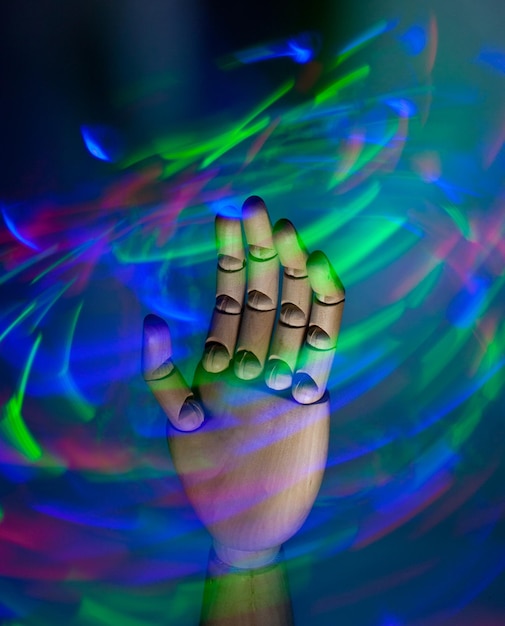 Foto close-up di una mano umana su uno sfondo colorato illuminato