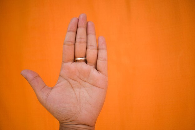 Foto close-up di una mano umana su uno sfondo arancione