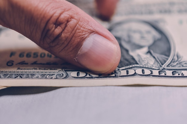 Photo close-up of human hand holding paper currencies on table