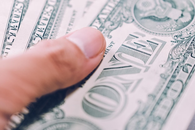 Photo close-up of human hand holding paper currencies on table