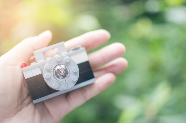 Photo close-up of human hand holding toy camera outdoors