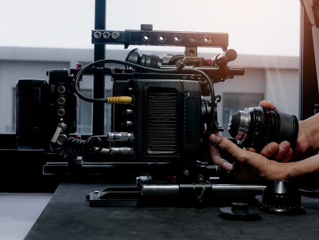 Photo close up human hand inserting the cinema lens into a movie camera mount.