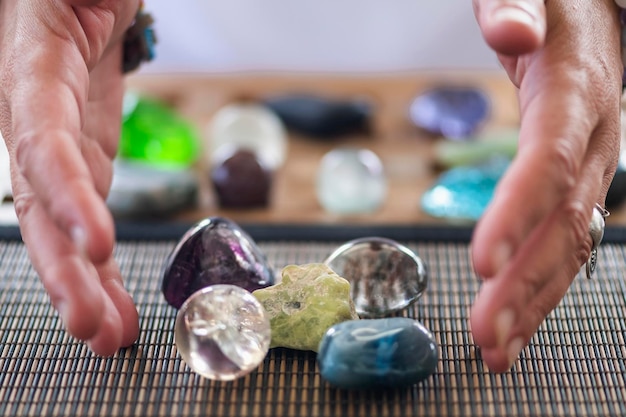 Close-up of human hand over multi colored gemstone on table