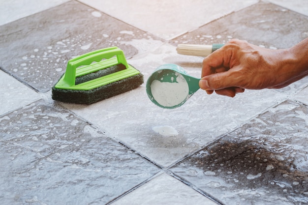 Close up a human hand pouring the detergent on the wet tile floor to clean it.