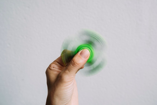 Foto close-up di una mano umana che fa girare un giratore verde contro uno sfondo bianco