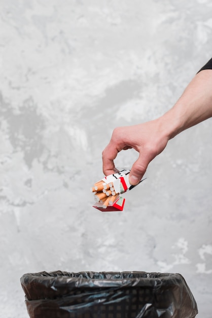 Photo close-up of human hand throwing packet of cigarettes