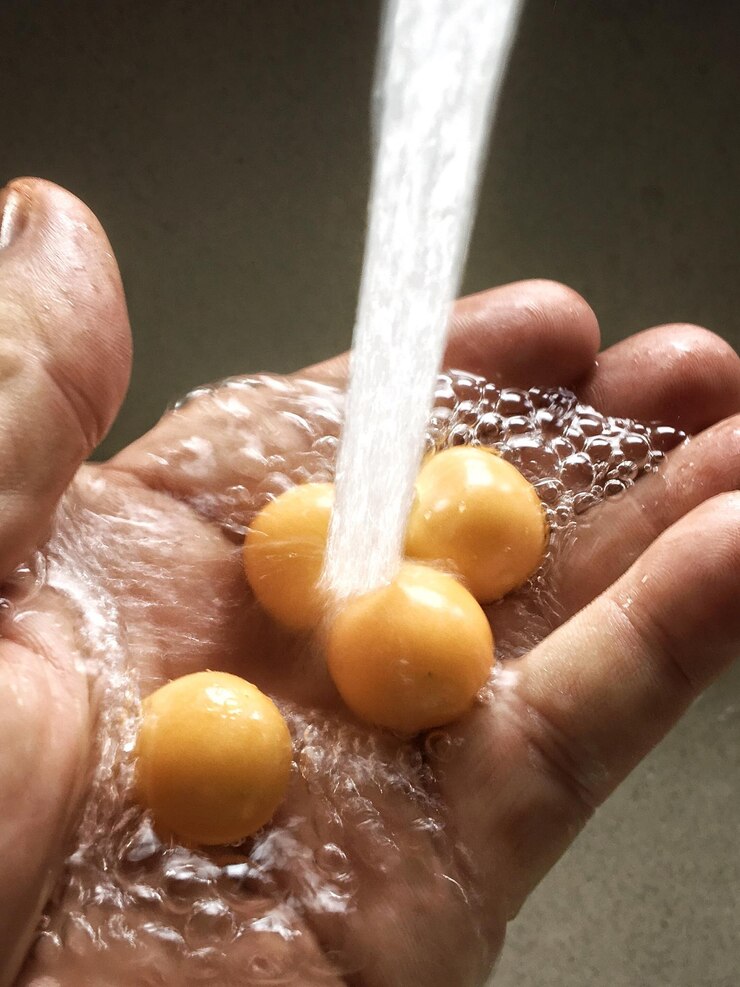 Photo close-up of human hand washing food under running water