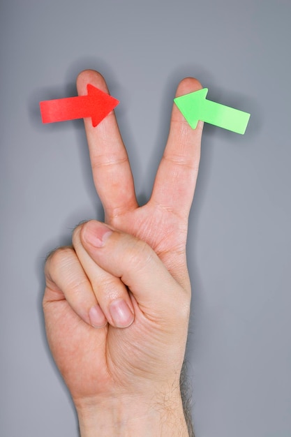 Photo close-up of human hand with arrow stickers against gray background