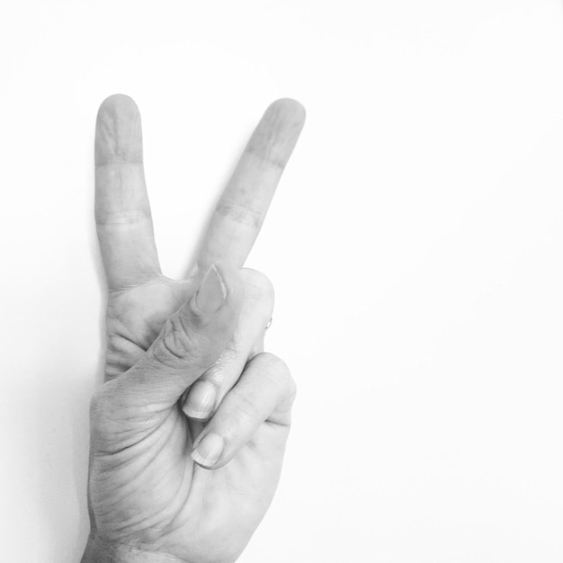 Photo close-up of human handpeace sign gesture against white background