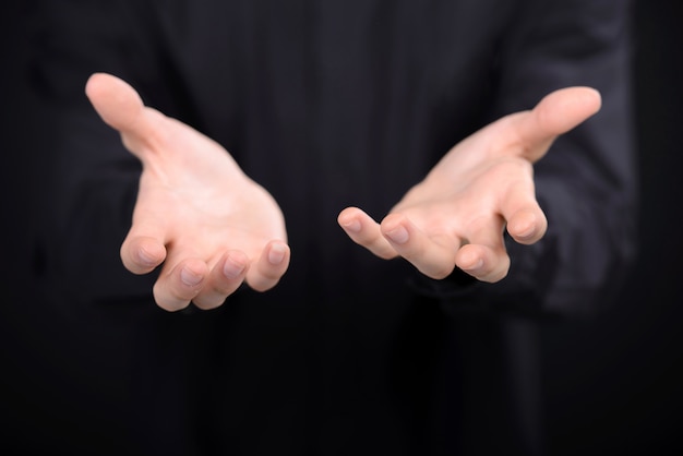 Close-up of human hands stretching out from the dark