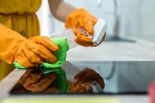 Close up on human hands in yellow gloves with spray cleaning wooden surface