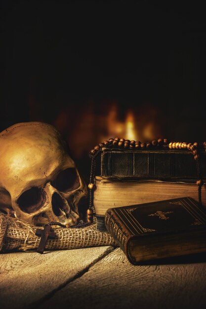 Foto close-up di un cranio umano e un rosario su un libro sopra il tavolo