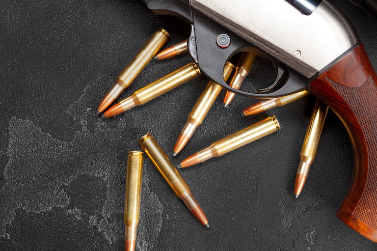 Photo close up of hunting shotgun and cartridges on dark grey surface