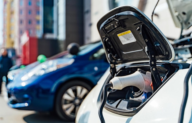 Primo piano della stazione di ricarica elettrica per auto ibrida con alimentazione collegata a un'auto elettrica in carica foto d'archivio