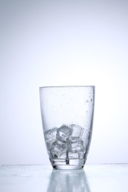 Foto close-up di cubetti di ghiaccio in bicchiere contro uno sfondo bianco