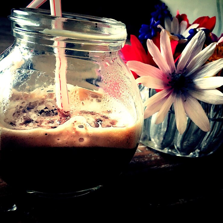 Photo close-up of iced coffee in glass container on table