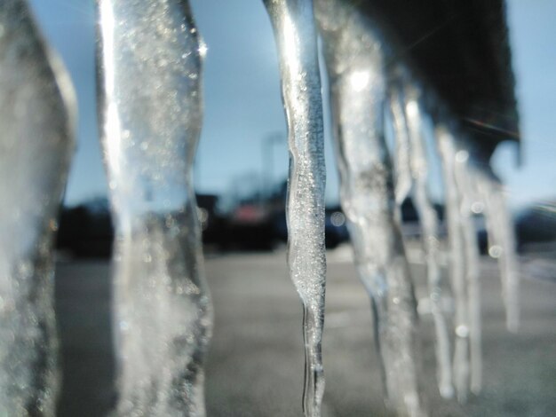 Photo close-up of icicles against sky during winter