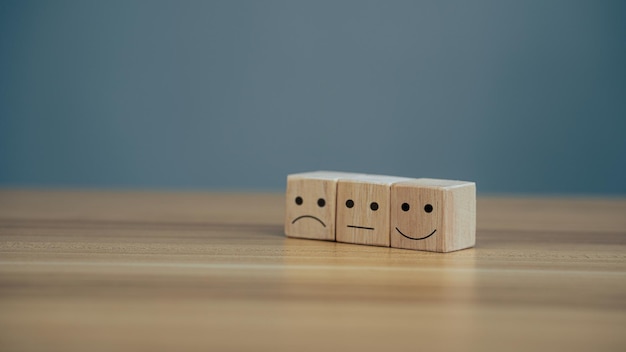 Close up icon smiley face and blurred sad face on wood\
cube