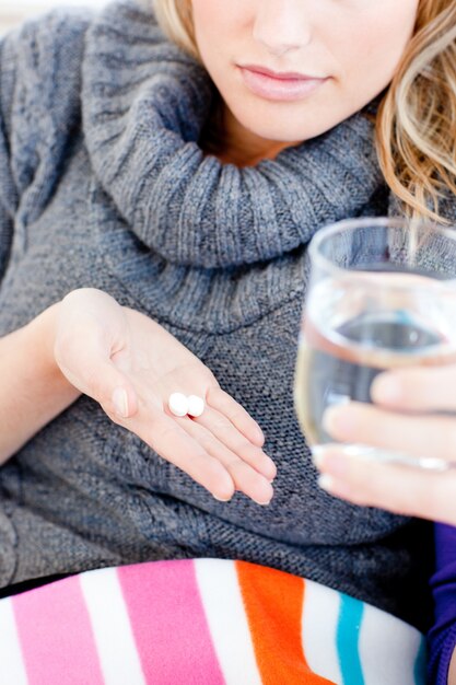 Primo piano di una donna malata che tiene le pillole e l'acqua