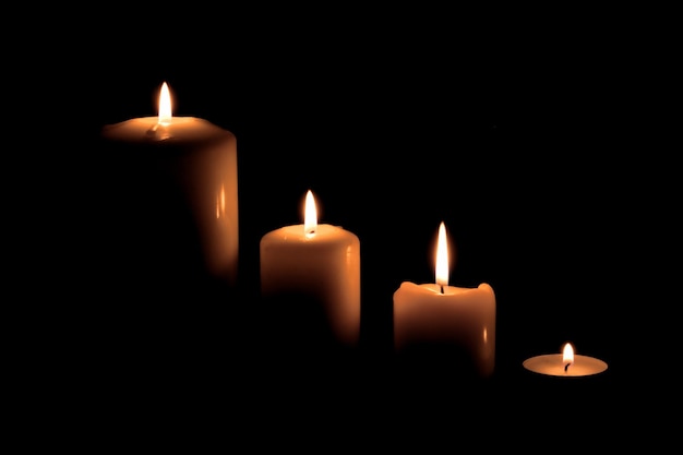 Близкий план освещенной свечи на черном фоне
