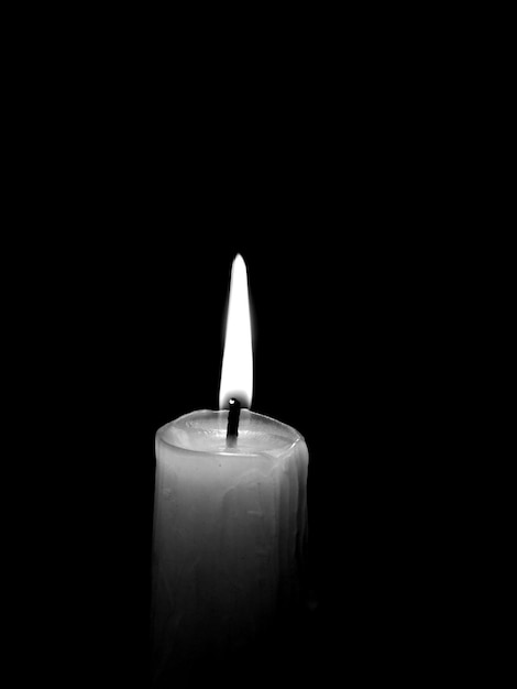 Photo close-up of illuminated candle over black background