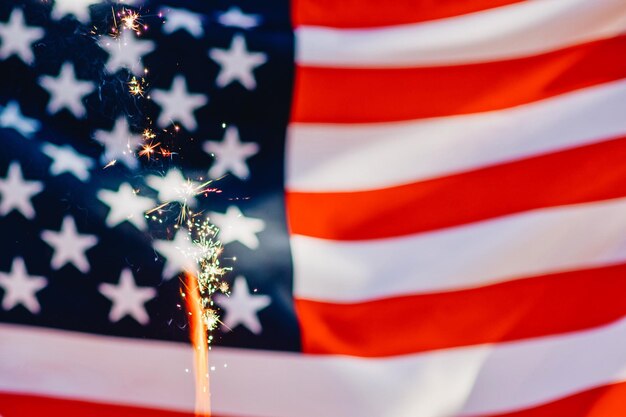 Foto close-up di fuochi d'artificio illuminati contro la bandiera americana