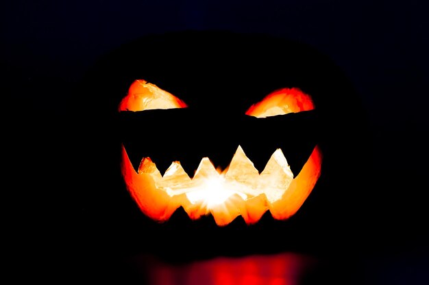 Photo close-up of illuminated jack o lantern against black background