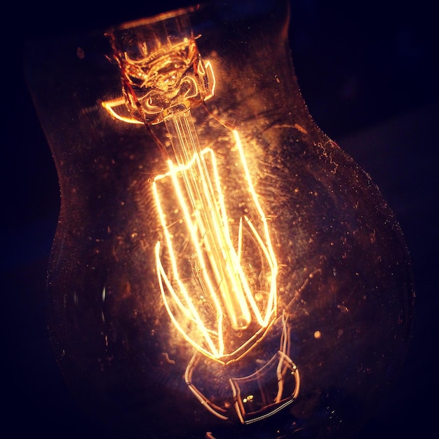 Photo close-up of illuminated light bulb against black background