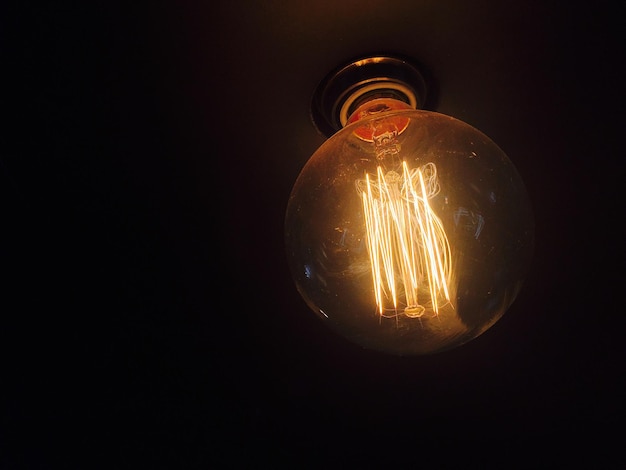 Close-up of illuminated light bulb against black background