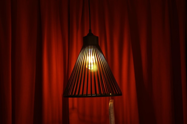 Photo close-up of illuminated pendant light against curtain