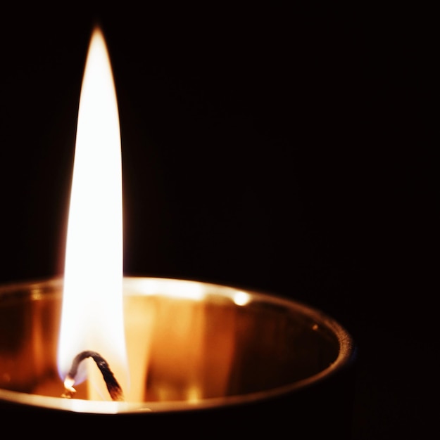 Photo close-up of illuminated tea light against black background