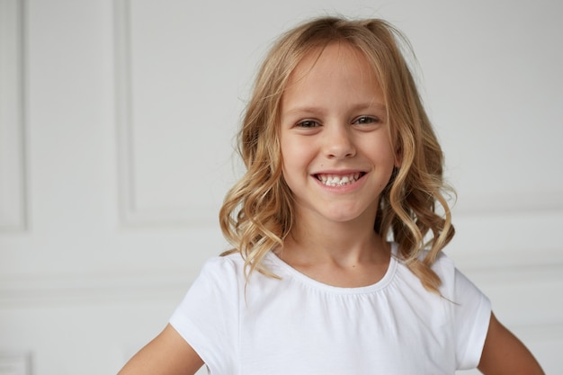 Close up image of an adorable smiling little girl showing her teeth chewing a gum .