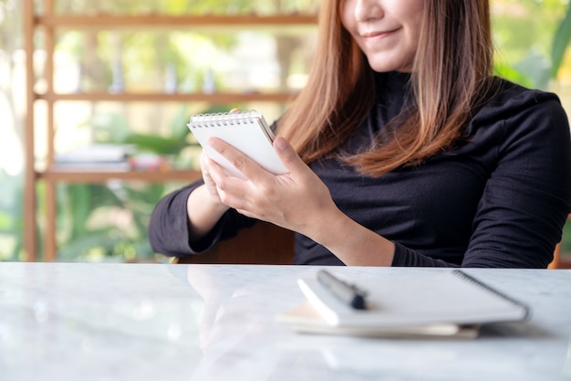 Close up image of a beautiful businesswoman holding and writing on notebook