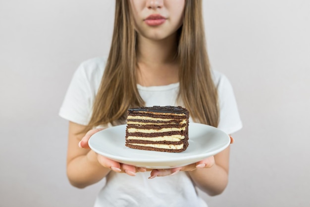 접시 에 초콜릿 케이크 한 조각 을 들고 있는 아름다운 젊은 여자 의 근접 이미지