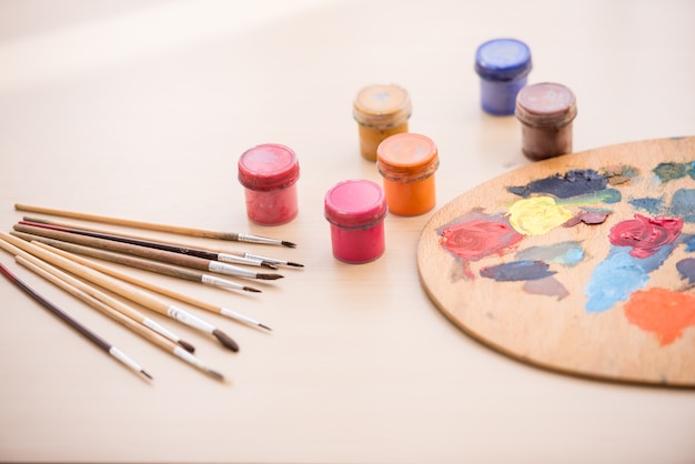 Close-up image of brushes, paints and palette on the table.