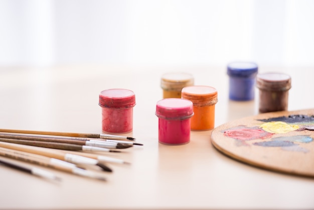 Close-up image of brushes, paints and palette on the table.