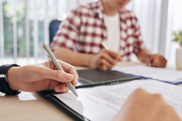 Close-up image of business people reading and discussing terms of contract at meeting