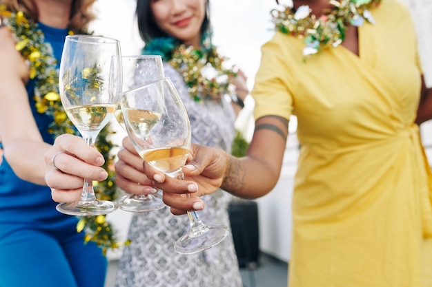 Immagine ravvicinata degli ospiti della festa di natale che brindano con bicchieri di champagne