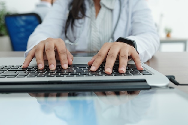 Close-up image of female general practitioner working on computer and entering patients data and diagnosis