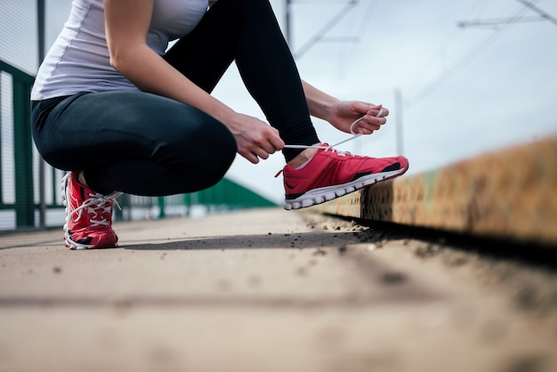 Photo close-up image of female runner tying shoelace.