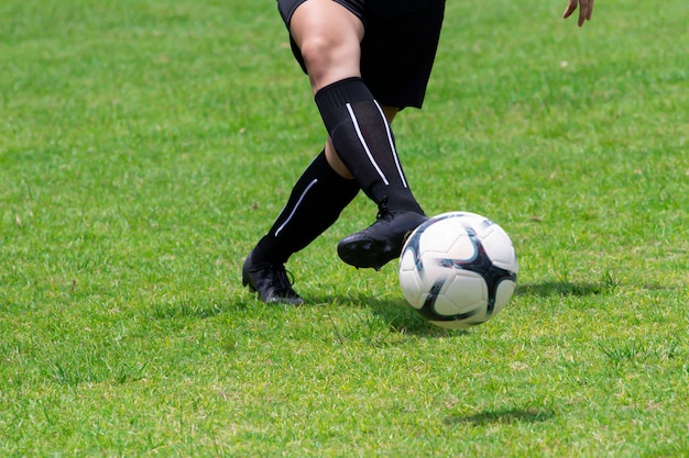 Close-up image. The footballers are using orange feet, the ball is on the lawn.